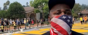  Justin wears an American flag a mask and stands in front of BLM mural