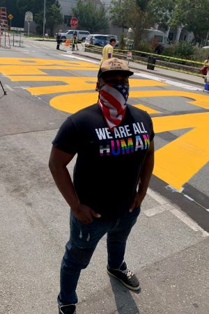 Justin stands in front of Black Lives Matter mural